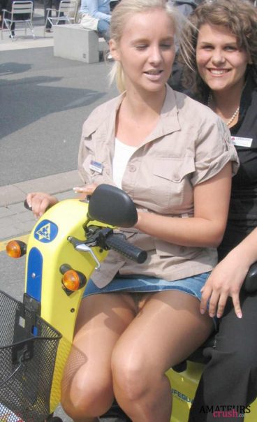 sitting on a scooter with a miniskirt and no panties having a oops upskirt moment with her friend