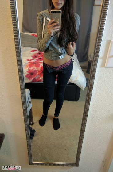 College girl making teasing selfie with her pants button open