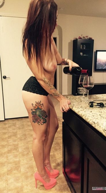 Sexy wife pouring wine in glass with no bra
